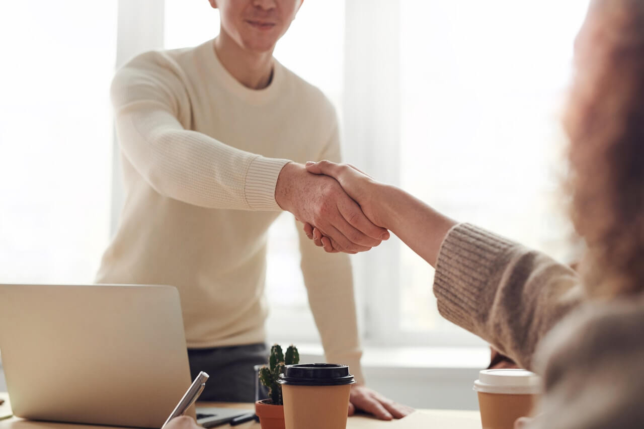 a property seller shakes hands with a buyer after selling their home